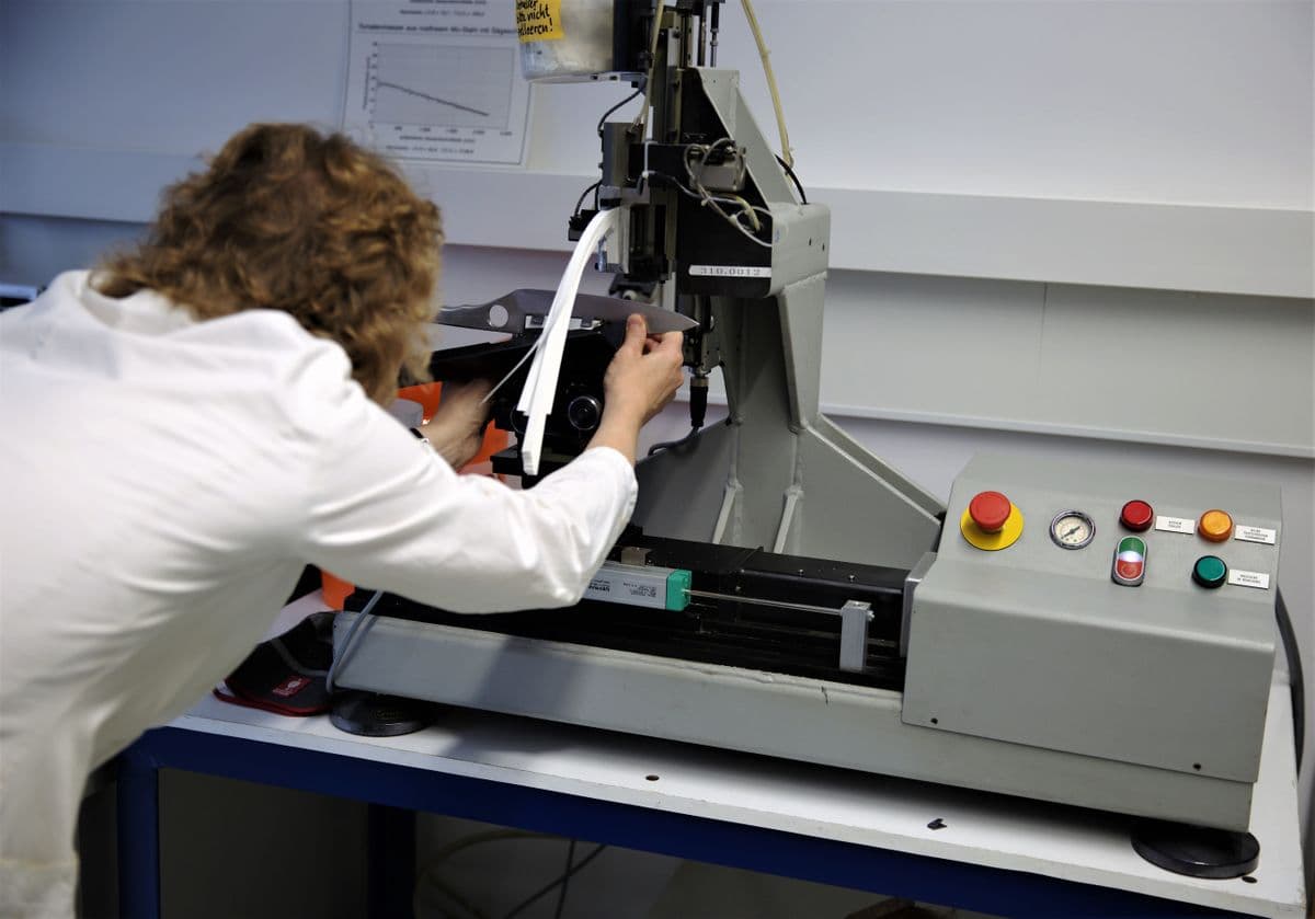 Technician operating a materials testing machine in the quality-control lab